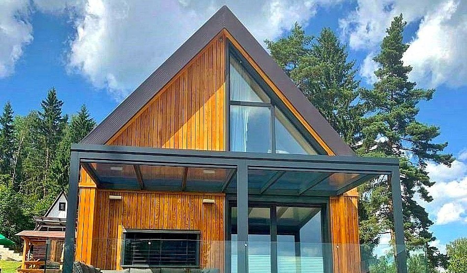 Áčková chata s modřínovým obkladem a proskleným štítem, pergola s terasou
